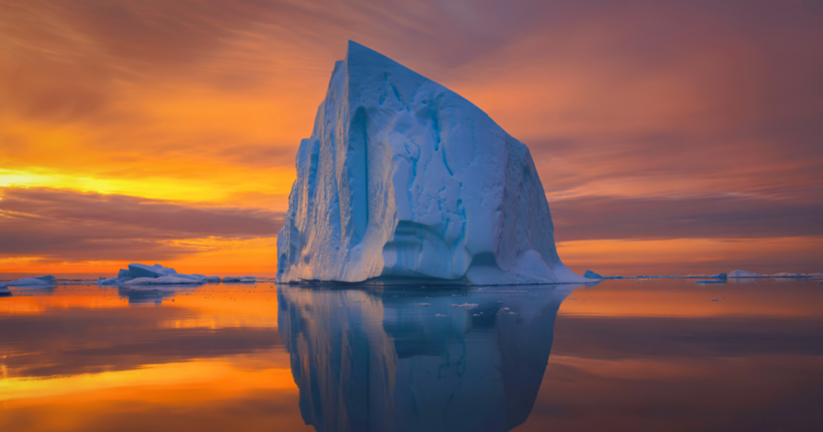 Iceberg reflecting on water sunset